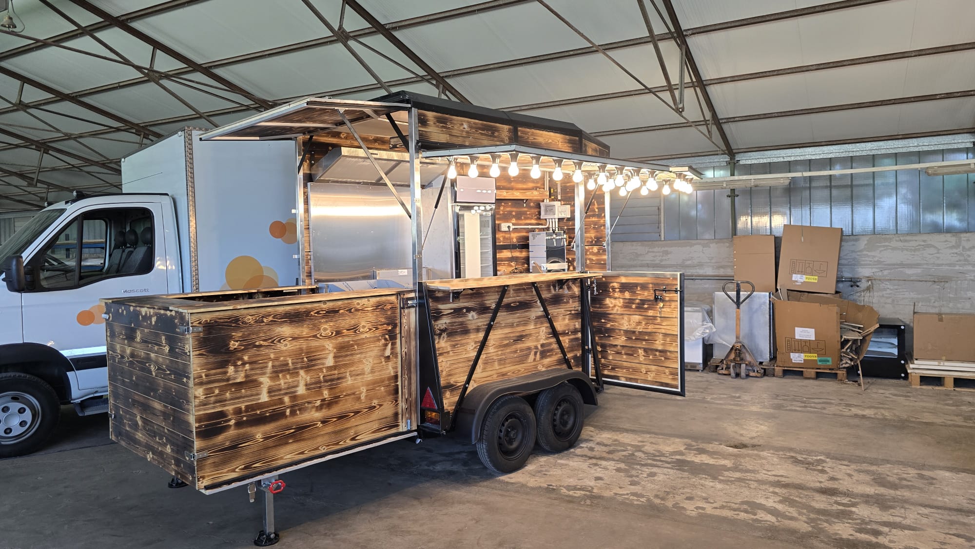 Il food trailer in legno fiammato realizzato davvero, con le luci a festone accese, nell'officina Tecno's